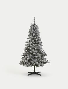 a small white christmas tree with snow on the top and bottom branches, in front of a gray background