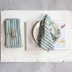 a plate and napkins on top of a table next to an open book,