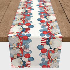 a table runner with red, white and blue decorations on it is sitting on a wooden surface