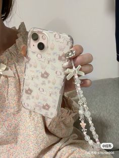 a woman holding up her phone case with charms attached to it