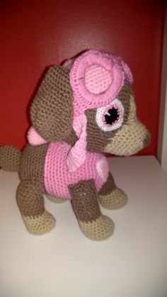 a crocheted stuffed dog wearing a pink hat