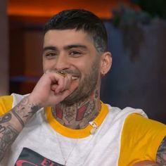 a man with tattoos and piercings on his face sitting in front of a camera