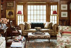 a living room filled with furniture and lots of windows covered in wood paneled walls