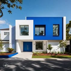 a blue and white modern house with trees in the front yard, on a sunny day