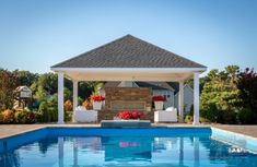 a pool with a gazebo next to it and flowers on the back drop area