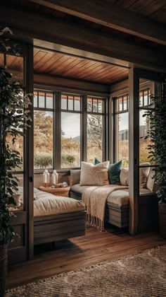 a living room filled with lots of windows next to a couch and coffee table on top of a hard wood floor