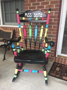 a chair made out of crayons sitting in front of a brick building with the word miss scitti on it