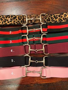 four different colored belts with metal buckles on each side and numbers in the middle