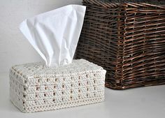 a tissue dispenser sitting next to a wicker basket with a cloth in it