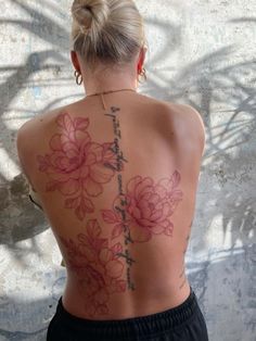 the back of a woman's body with flowers tattooed on her upper and lower back