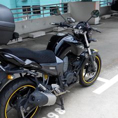 a black motorcycle parked in a parking lot next to a blue and white building with graffiti on it