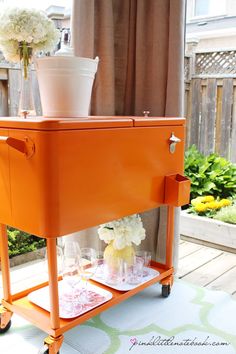 an orange cart with flowers and wine glasses on it