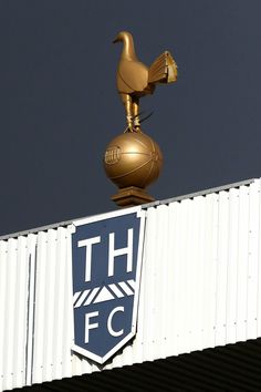 a golden bird on top of a building with the logo of the soccer club thfc