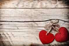 two red heart shaped felts tied with twine on rustic wooden table top view