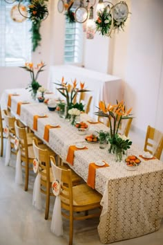 a long table with orange and white place settings