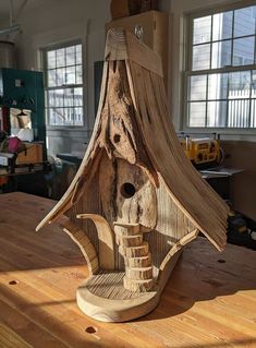 a birdhouse made out of wood sitting on top of a wooden table in a room