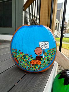 a blue pumpkin sitting on top of a wooden table next to a green ball and a sign