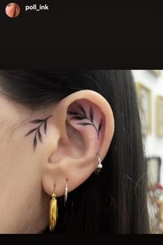 a woman with black ink on her ear and behind the ear is a leaf tattoo