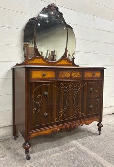 an old fashioned dresser with a mirror on it's top and drawers in the middle