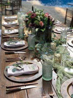 an outdoor table set with place settings and flowers