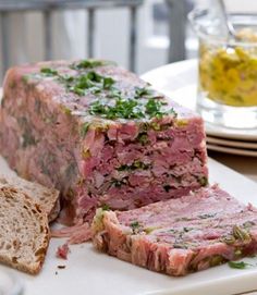 a meatloaf sandwich cut in half on a white plate with bread and water