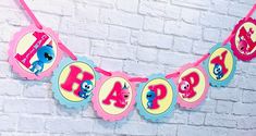 a pink and blue birthday banner hanging on a brick wall