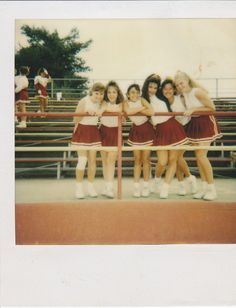 a group of young women standing next to each other in front of bleachers