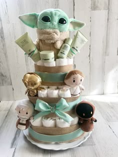 a star wars themed diaper cake with baby items on it and an infant yoda doll in the center