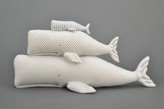 two stuffed animals are sitting on pillows in the shape of a whale and a fish