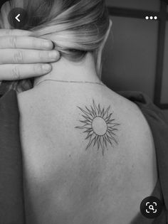 the back of a woman's shoulder with a sun tattoo on it