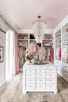 a walk in closet filled with lots of white furniture and pink flowers on the counter