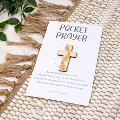 a card with a cross on it sitting next to a plant and some leaves in the background