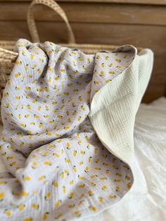 a yellow and white bag sitting on top of a bed next to a wicker basket