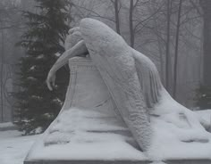 an angel statue sitting in the middle of a snow covered ground next to a pine tree