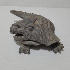 a wooden carving of a lizard on a white surface