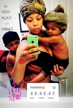 a woman taking a selfie with her two children on her cell phone in front of a poster