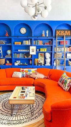 a living room filled with orange and blue furniture next to a book shelf full of books