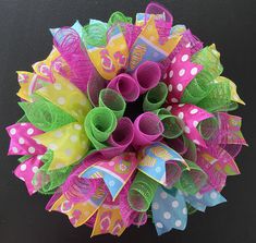 a close up of a wreath made out of colorful ribbons and streamers on a black background