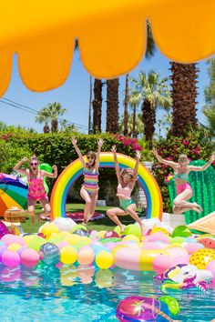 children jumping into the pool with balloons and inflatables around them on a sunny day