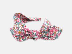 Designed for comfort and ease of wear, this women's side bow headband is the perfect way to add the finishing touch to your outfit. This playful design features a detachable bow, allowing you to create different looks with your headband. Handmade using the softest Liberty London Tana Lawn cotton, this headband is kind to the hair and protects from any tension breakage. Liberty London Betsy Ann E pink print 100% Liberty London Tana Lawn cotton Detachable bow and wide fabric base Flexible recyclab Adjustable Decorative Bow Hair Accessory For Summer, Adjustable Hair Accessories With Decorative Bow For Summer, Summer Bow Headband, Summer Decorative Bow Headband, Adjustable Bow With Matching Headband For Spring, Adjustable Hair Accessories With Decorative Bow For Spring, Summer Headband With Decorative Bow, Spring Bow Headband Hair Accessories, White Headband With Bow Tie