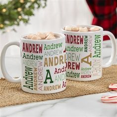 two coffee mugs with hot chocolate in them on a table next to christmas decorations