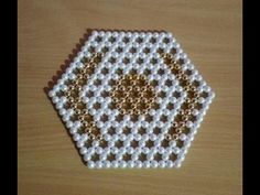 a beaded hexagonal object sitting on top of a wooden table next to scissors