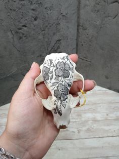 a hand holding an animal skull with flowers on it