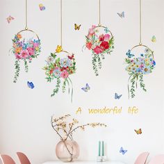 flowers and butterflies are hanging from the ceiling above a dining room table with pink chairs