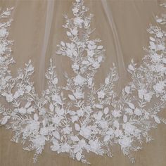 white flowers and leaves are on the sheer fabric that is covering the wedding veils