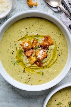 two bowls filled with soup and topped with croutons