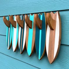 several surfboards mounted to the side of a blue wooden wall hanging on a hook