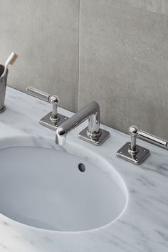 a bathroom sink with two faucets and a toothbrush holder on the side