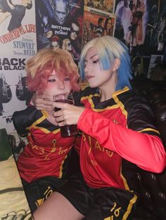 two cosplayed people sitting on a couch with drinks in front of them