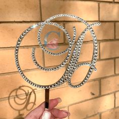 a hand holding a cake topper with the letter q on it's side